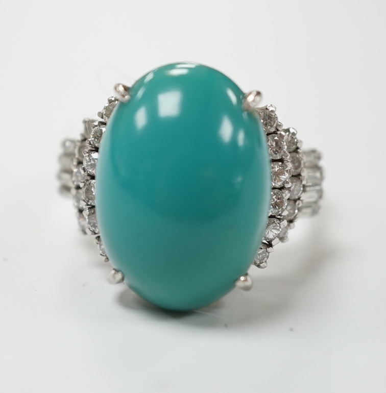 A modern white metal (stamped Pt900) and cabochon turquoise set dress ring, with baguette and round cut diamond set shoulders, size M, gross weight 12.4 grams. Condition - fair